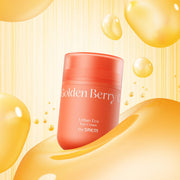 ProtoClinical k-beauty The SAEM Urban Eco Golden Berry C Eye Cream 30ml coral-orange eye cream jar standing upright among glossy golden serum drops on a yellow striped background