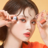 ProtoClinical k-beauty 16BRAND Sixteen Eye Magazine (7colors) close-up of a model holding the dual eyeshadow compact and applicator against a warm peach background