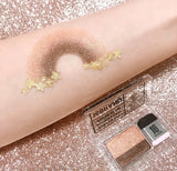 ProtoClinical k-beauty 16BRAND Sixteen Eye Magazine (7colors) glitter arm swatch with curved bronze shimmer and brown matte shadow above an open dual eyeshadow compact on a sparkly rose-gold background