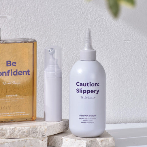 ProtoClinical k-beauty withbecon Caution Slippery Hair Treatment 300ml single upright pale gray treatment bottle centered between warm beige and pale blue side panels