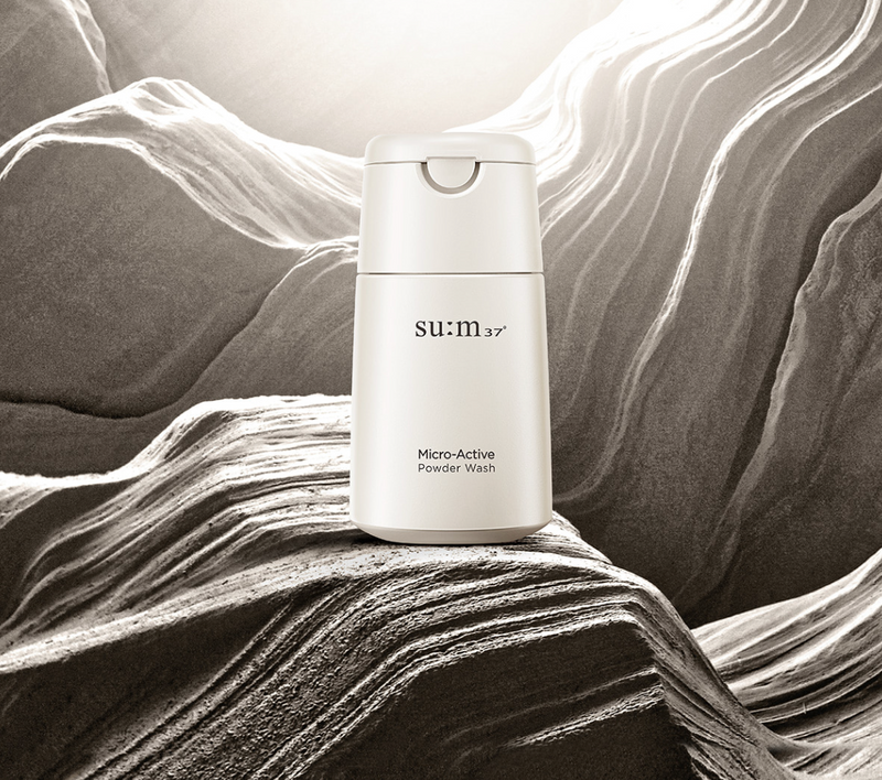 ProtoClinical k-beauty su:m37 Micro-Active Powder Wash 60g product packaging against a dark gray and cream background.