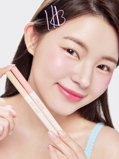 ProtoClinical k-beauty THE FACE SHOP EYE RISE Dual Under Eye Maker 0.6g single slim under-eye maker package centered vertically on a pale peach and gray background with soft cream highlights