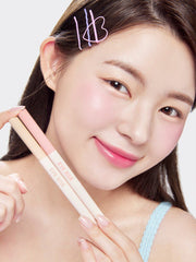 ProtoClinical k-beauty THE FACE SHOP EYE RISE Dual Under Eye Maker 0.6g single slim under-eye maker package centered vertically on a pale peach and gray background with soft cream highlights