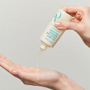 ProtoClinical k-beauty DEWYTREE AC Deep Moisture Barrier Calming Ampoule 60ml upside-down cream bottle dispensing ampoule into an open palm, with an aqua cap and bare hands on a light background