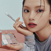 ProtoClinical k-beauty muted beige beauty graphic with a rosy center, pale aqua left edge, and a dark lower-right shadow.