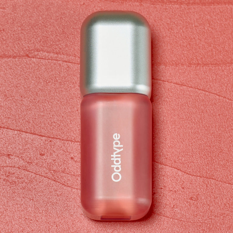 ProtoClinical k-beauty Oddtype Unseen Blur Tint single upright lip tint tube centered on a coral pink background
