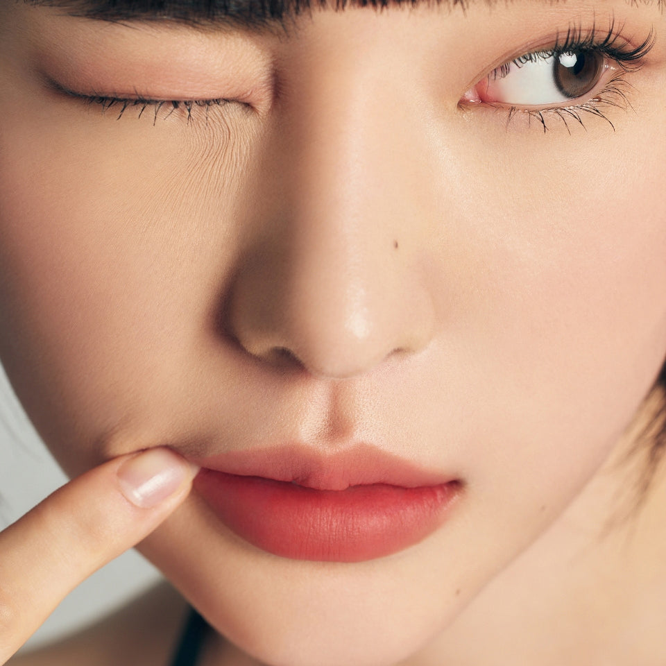 ProtoClinical k-beauty Oddtype Unseen Blur Tint single upright peach lip tint tube centered on a warm beige and taupe background