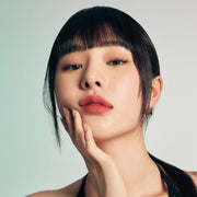 ProtoClinical k-beauty Oddtype Unseen Blur Tint single upright rosy brown lip tint tube with a dark cap on a pale aqua and taupe background