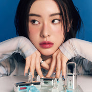 ProtoClinical k-beauty Oddtype Unseen Mirror Tint single upright peach lip tint tube centered on a cool blue background with dark navy side gradients