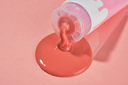 ProtoClinical k-beauty PAUL MEDISON Deep Red Pore Peel Off Pack 155ml close-up of coral-red peel-off cream squeezing from a white tube onto a peach-pink background