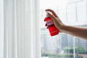 ProtoClinical k-beauty PAUL MEDISON Signature Body Mist 211ml #Baby Powder held in one hand as a single translucent pink-red body mist bottle beside a sheer white curtain