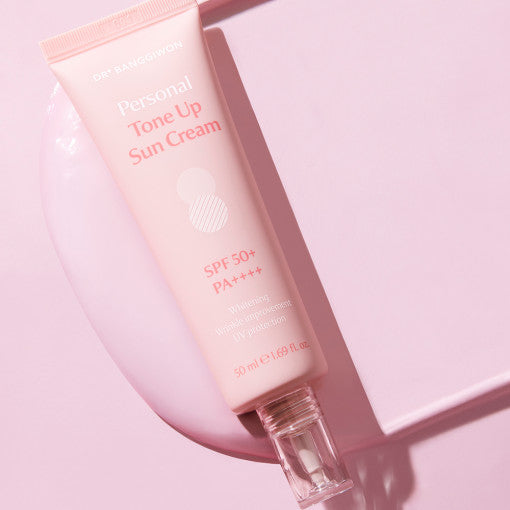 ProtoClinical k-beauty DR.BANGGIWON Personal Tone Up Sun Cream #01 Rosy 50ml SPF50+ PA++++ single rosy pink sun cream package centered vertically on a pale pink background.