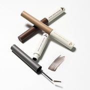 ProtoClinical k-beauty TONYMOLY Eye Tone Skinny Brow Mascara 3.5g single slim brow mascara tube angled diagonally in taupe and black on a white background