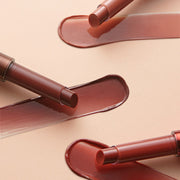ProtoClinical k-beauty TONYMOLY Get It Tint Glaze Balm three glossy beige and brown swatches stacked horizontally on a pale peach background