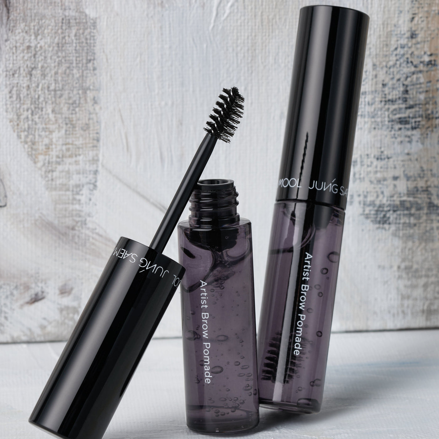 ProtoClinical k-beauty JUNGSAEMMOOL Artist Brow Pomade 7.5g soft beige and taupe beauty graphic with a darker central form on a light background.