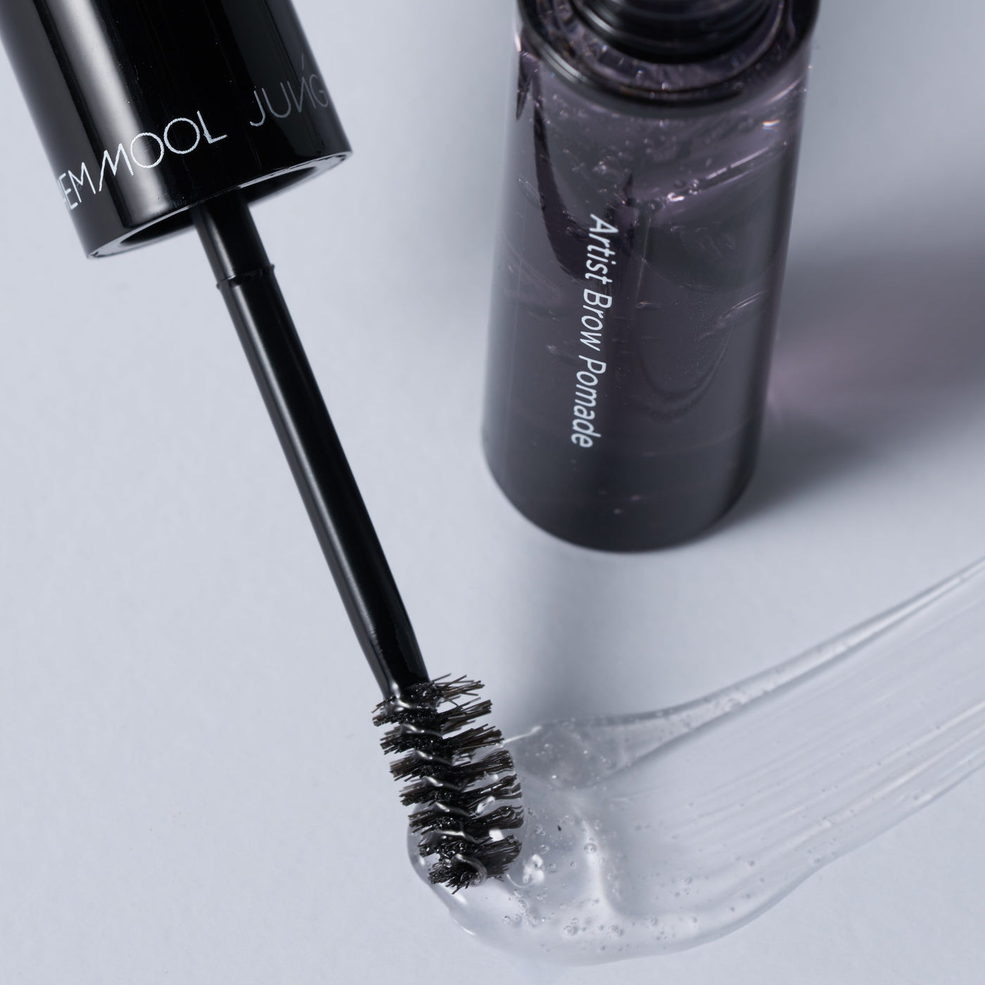 ProtoClinical k-beauty JUNGSAEMMOOL Artist Brow Pomade 7.5g dark brow pomade beauty graphic with layered gray and charcoal forms on a light background.