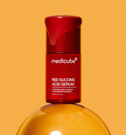 ProtoClinical k-beauty MEDICUBE: Red Succinic Acid Serum (30ml) single upright red serum bottle on a warm orange background
