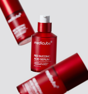 ProtoClinical k-beauty MEDICUBE: Red Succinic Acid Serum (30ml) single upright red serum bottle on a soft pink background with pale blue side accents