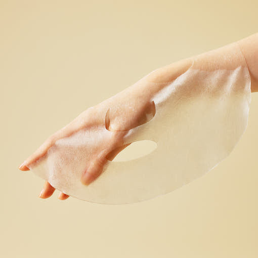 ProtoClinical k-beauty [SOME BY MI] Yuja Niacin Blemish Care Serum Mask 25g*10ea unfolded translucent sheet mask draped over a hand on a soft yellow background