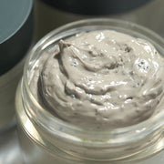 ProtoClinical k-beauty [Pyunkang Yul] Calming Pore Clear Wash Off Pack 100g open clear jar filled with gray clay mask texture beside a dark green lid on a soft background