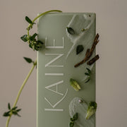 ProtoClinical k-beauty single dark green vertical beauty package centered in a square crop on a muted taupe background