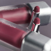 ProtoClinical k-beauty Oddtype Unseen Blur Tint (562, 655, 788) single upright lip tint tube centered on a rosy mauve and pale aqua background