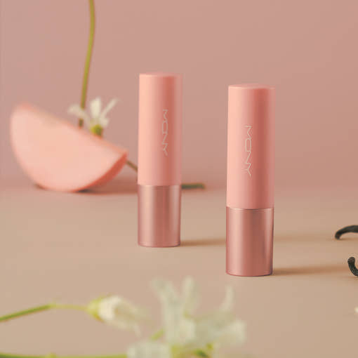 ProtoClinical k-beauty [MACQUEEN New York] Better Than Kiss Lip Balm 3.5g (3-type) two soft pink lip balm tubes standing upright beside peach slices and small flowers on a warm beige background