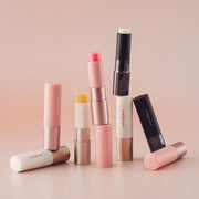ProtoClinical k-beauty [MACQUEEN New York] Better Than Kiss Lip Balm 3.5g (3-type) six lip balm tubes arranged upright and sideways on a soft peach background with coral, ivory, and black packaging