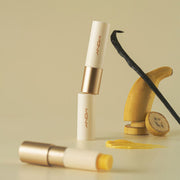 ProtoClinical k-beauty [MACQUEEN New York] Better Than Kiss Lip Balm 3.5g (3-type) two ivory lip balm tubes with yellow balm exposed beside banana slices and vanilla pods on a light cream background