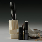 ProtoClinical k-beauty [MACQUEEN New York] Better Than Kiss Lip Balm 3.5g (3-type) two black lip balm tubes with one clear balm exposed beside coconut pieces on a pale gray background