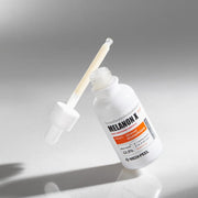 ProtoClinical k-beauty MEDIPEEL Melanon X Ampoule Light 30ml two pale beige ampoule packaging shapes on a soft gray background