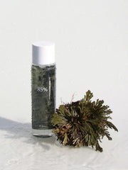 ProtoClinical k-beauty beauty graphic with a dark horizontal band beneath soft beige and green tones on a pale background.