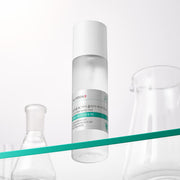 ProtoClinical k-beauty ILLIYOON Cica Trouble Clear Body Mist 200ml shown as a clear bottle with a white cap on a diagonal teal shelf beside glass vessels on a bright white backdrop