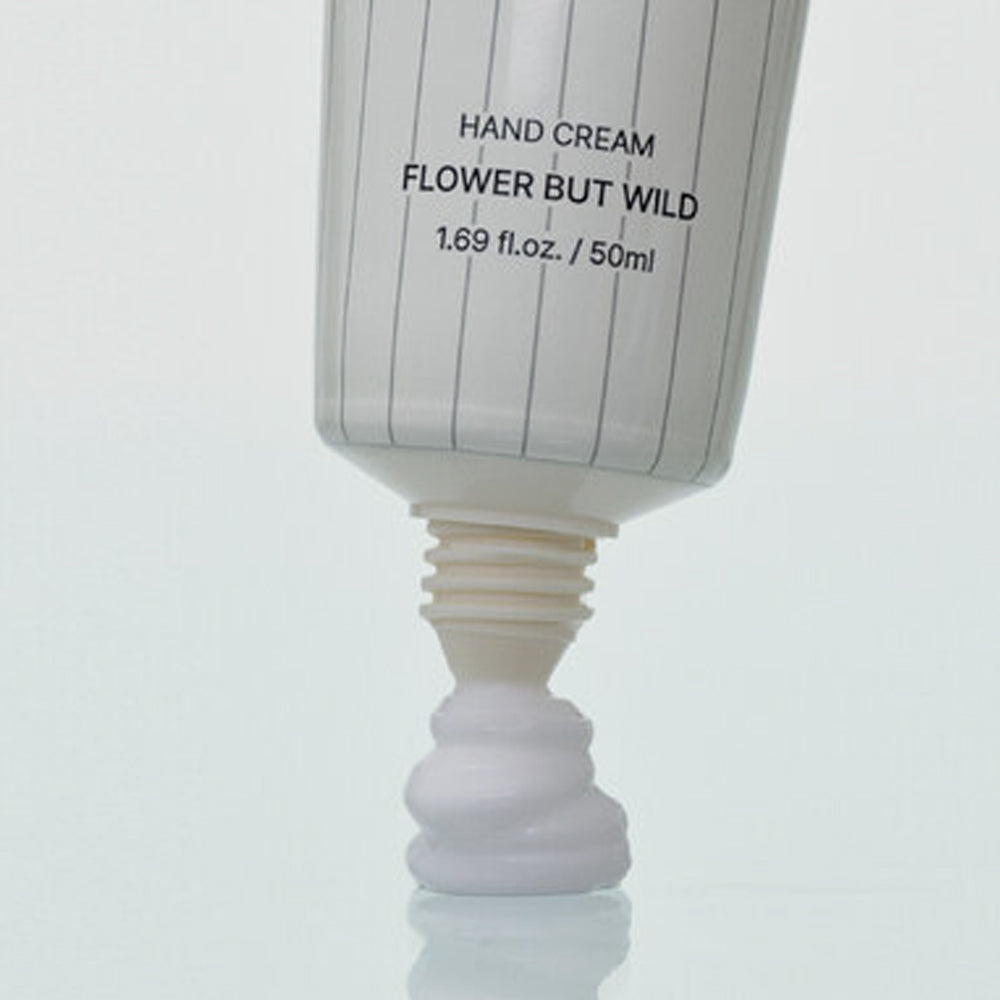 ProtoClinical k-beauty SENNOK Hand Cream Flower But Wild 50ml in a close-up of the white tube dispensing a dollop of cream from the open nozzle onto a pale blue surface