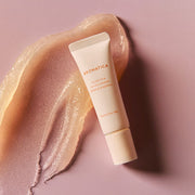 ProtoClinical k-beauty AROMATICA Glow Vita Lip Volumizer Orange & Neroli 10g full beige tube laid over a shimmering nude gloss smear on a soft pink background