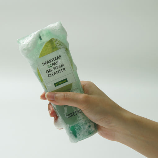 ProtoClinical k-beauty CURESYS Heartleaf Acpair Gel Foam Cleanser 150ml in a mint-green foamy cleanser tube held in one hand against a light gray background