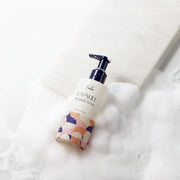 ProtoClinical k-beauty Foellie Capsule Feminine Wash 200ml bottle angled in white foam with a navy pump and a peach-patterned lower label
