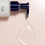 ProtoClinical k-beauty Foellie Capsule Feminine Wash 200ml close-up of a navy pump with a clear gel droplet dotted with microcapsules on a pale pink background