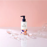 ProtoClinical k-beauty Foellie Capsule Feminine Wash 200ml upright bottle on a glossy white surface with translucent spheres and spilled liquid against a pink background