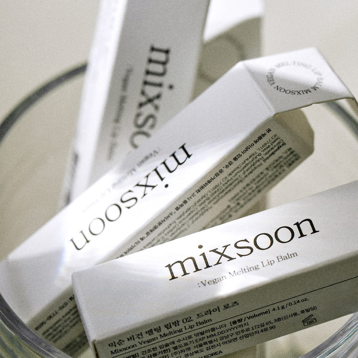 ProtoClinical k-beauty mixsoon Vegan Melting Lip Balm 4.1g single pale lip balm silhouette centered upright on a white background with dark gray top and base accents