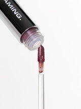 ProtoClinical k-beauty NAMING Dewy Glass Lip Tint (6colors) close-up of a black lip tint tube opening with a berry-toned applicator wand on a pale gray background