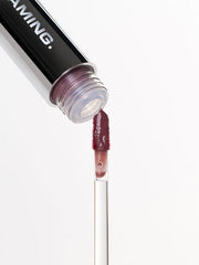 ProtoClinical k-beauty NAMING Dewy Glass Lip Tint (6colors) close-up of a black lip tint tube opening with a berry-toned applicator wand on a pale gray background