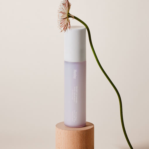 ProtoClinical k-beauty Huxley Hand Cream Mist 35ml #Sunset Fog with warm beige and charcoal packaging forms on a pale background