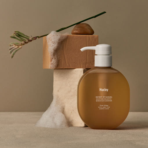 ProtoClinical k-beauty cosmetic packaging in warm brown tones on a taupe background.