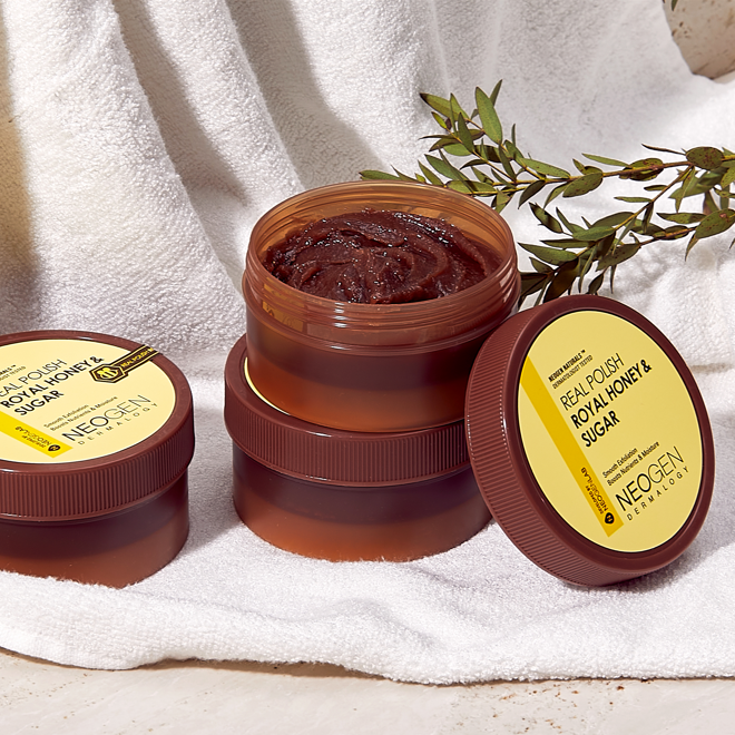 ProtoClinical k-beauty NEOGEN Dermalogy Real Polish - Royal Honey & Sugar Scrub 100g in an open amber-brown jar filled with brown scrub, with the round lid propped behind on a pale background