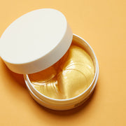 ProtoClinical k-beauty NEOGEN SUR.MEDIC+ Perfection 100TM 24K Gold Eye Patch 75g/60ea open round white jar with gold hydrogel eye patches and a tilted lid on a bright orange background