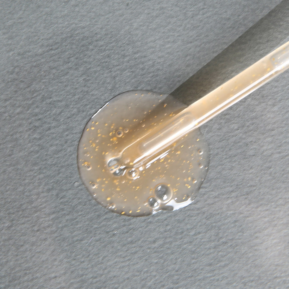 ProtoClinical k-beauty warm beige beauty product detail with soft gray tones on a light background.