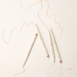 ProtoClinical k-beauty [TOO COOL FOR SCHOOL] Artclass Glam Under Liner 0.2g/0.7g (4 Colors) four cream liner pens arranged diagonally on a light cream background with peach and beige swatch lines