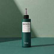 ProtoClinical k-beauty [MANYO FACTORY] BIOXYL Anti-Hair Loss Treatment 200ml with a muted teal product silhouette on a dark background