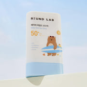 ProtoClinical k-beauty Round Lab Baby Mild Sun Stick 21g (SPF50+ PA++++) single upright beige sun stick container on a white background with soft blue lower corners.